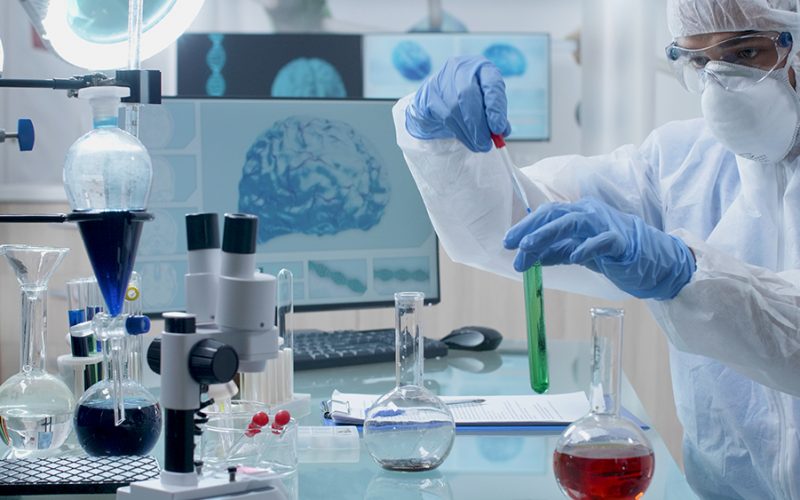 Researcher chemist doctor with ppe equipment doing chemical experiment using medical transparent glasses mixing liquid solution during microbiology experiment in hospital laboratory. Medicine concept