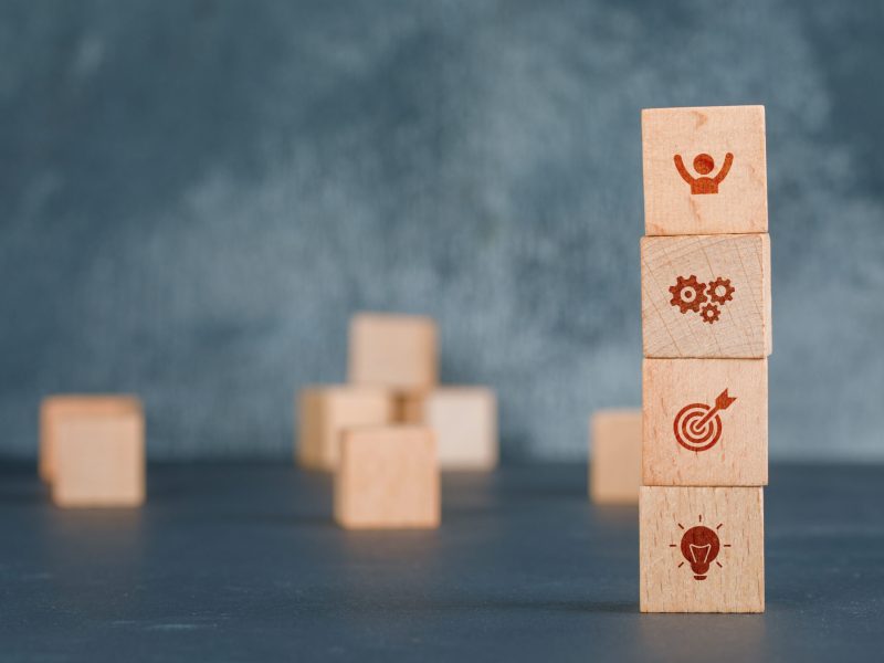 Conceptual of business with wooden blocks column with icons on dark color background side view. free space for your text horizontal image